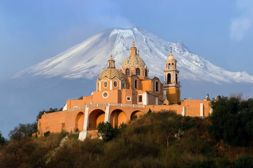 A baroque church in front of a volcano in Mexico