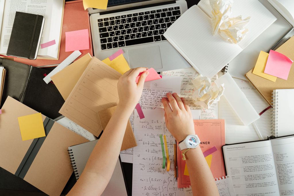 messy desk covered in notes, post-its, and computer showing information overload