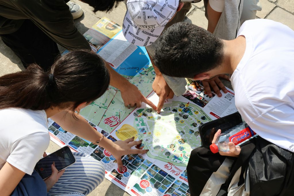 Four people bent over a map on the ground trying to make a decision